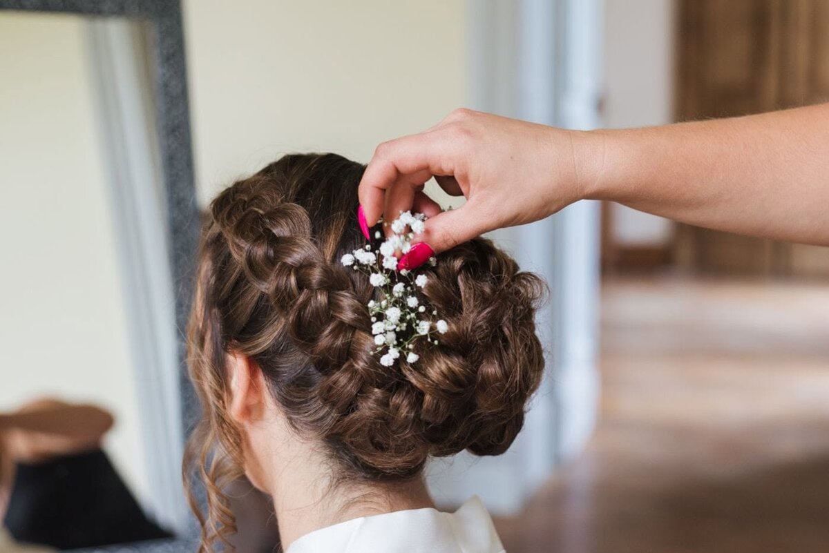 Chignon tressé de mariée réalisé chez Myst Hair, orné de gypsophile